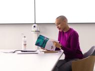 Employee alone in a meeting room in front of her laptop with notes sheets and water bottle