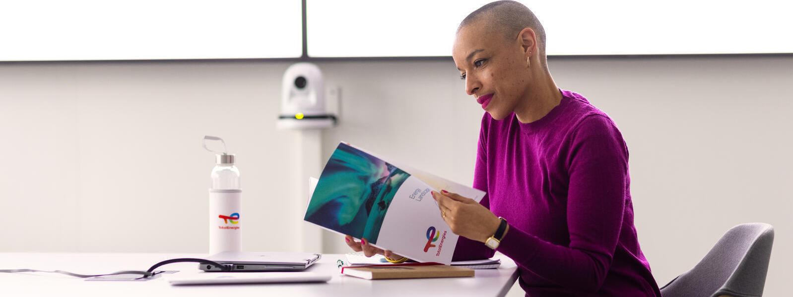 Employee alone in a meeting room in front of her laptop with note sheets and water bottle