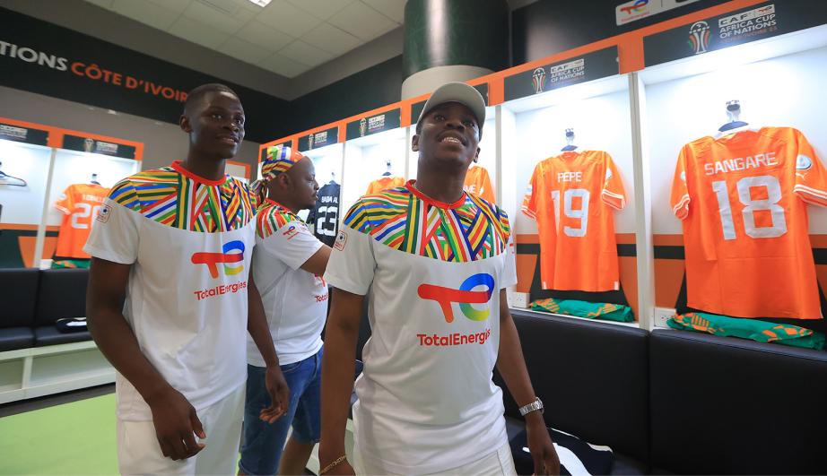 Personnes dans une salle exposant des maillots de football - voir description détaillée ci-après