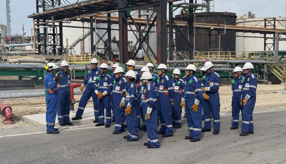 Group of people in work clothes, within an industrial plant - see detailed description hereafter